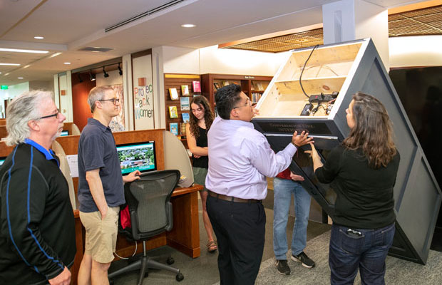 A student helps Associate Professor Sarah Sweeney stand up a phone booth that is part of her art installation in Scribner Library