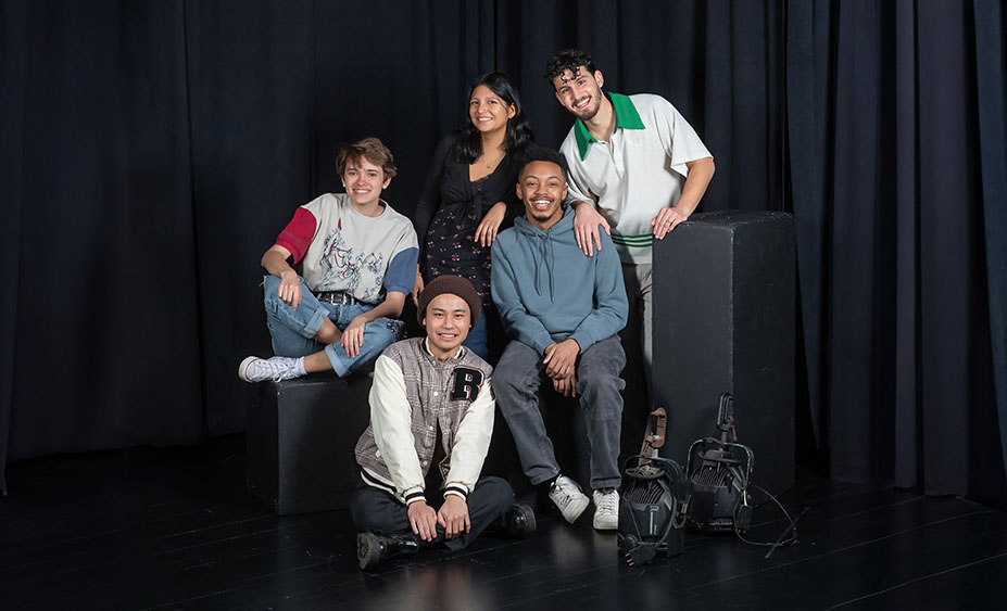 The five inaugural Miranda Fellows at Skidmore pose in a theater studio in front of a black curtain